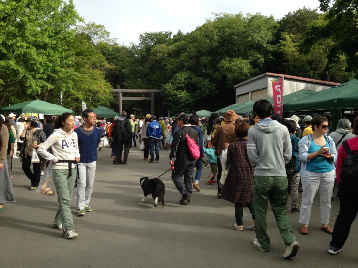 a crowd of people walking down a street with tents