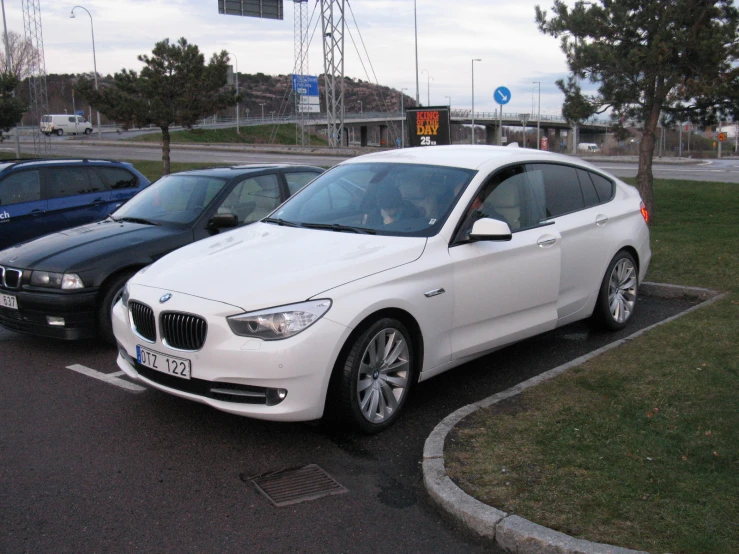 two white bmw cars in parking spaces at a station