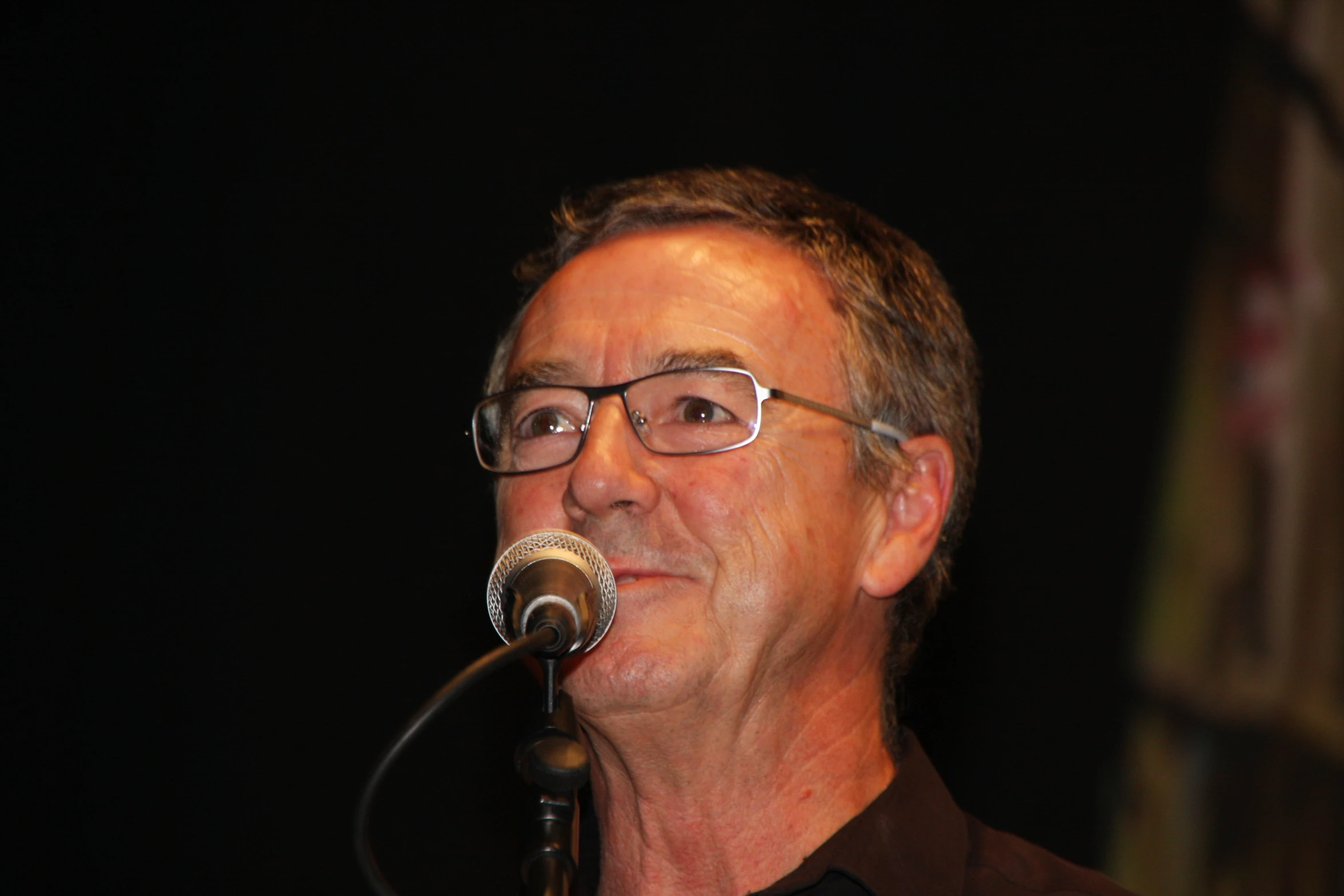a man standing behind a microphone with the black background