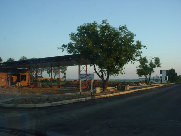 a gas station sitting next to a road under a tree