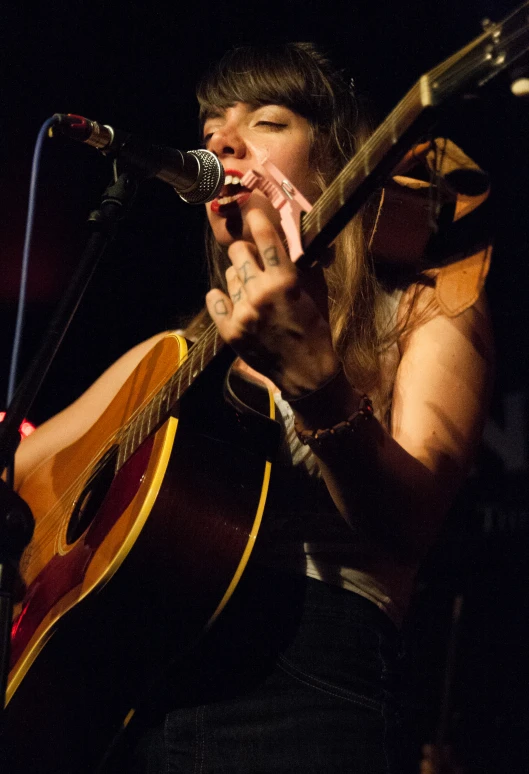 a woman is holding a guitar up to her mouth