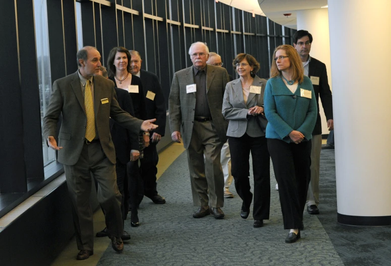 a group of people in business attire walk down a hallway