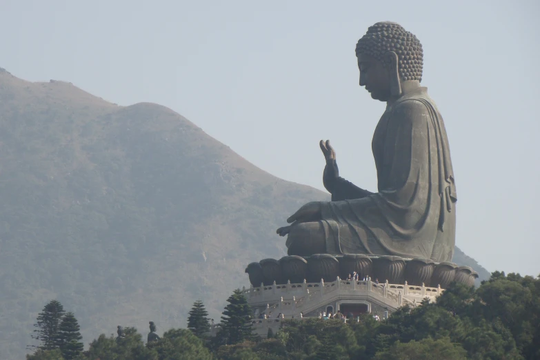large buddha statue with mountain backdrop in daylight