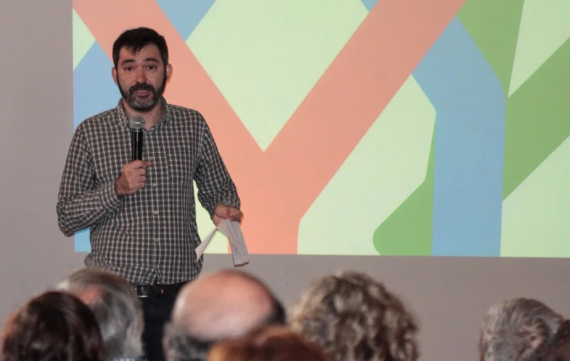 a man standing in front of a crowd of people holding a microphone