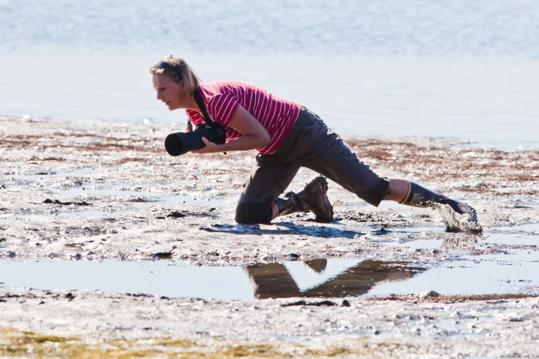 a person is kneeling on some sand with a camera