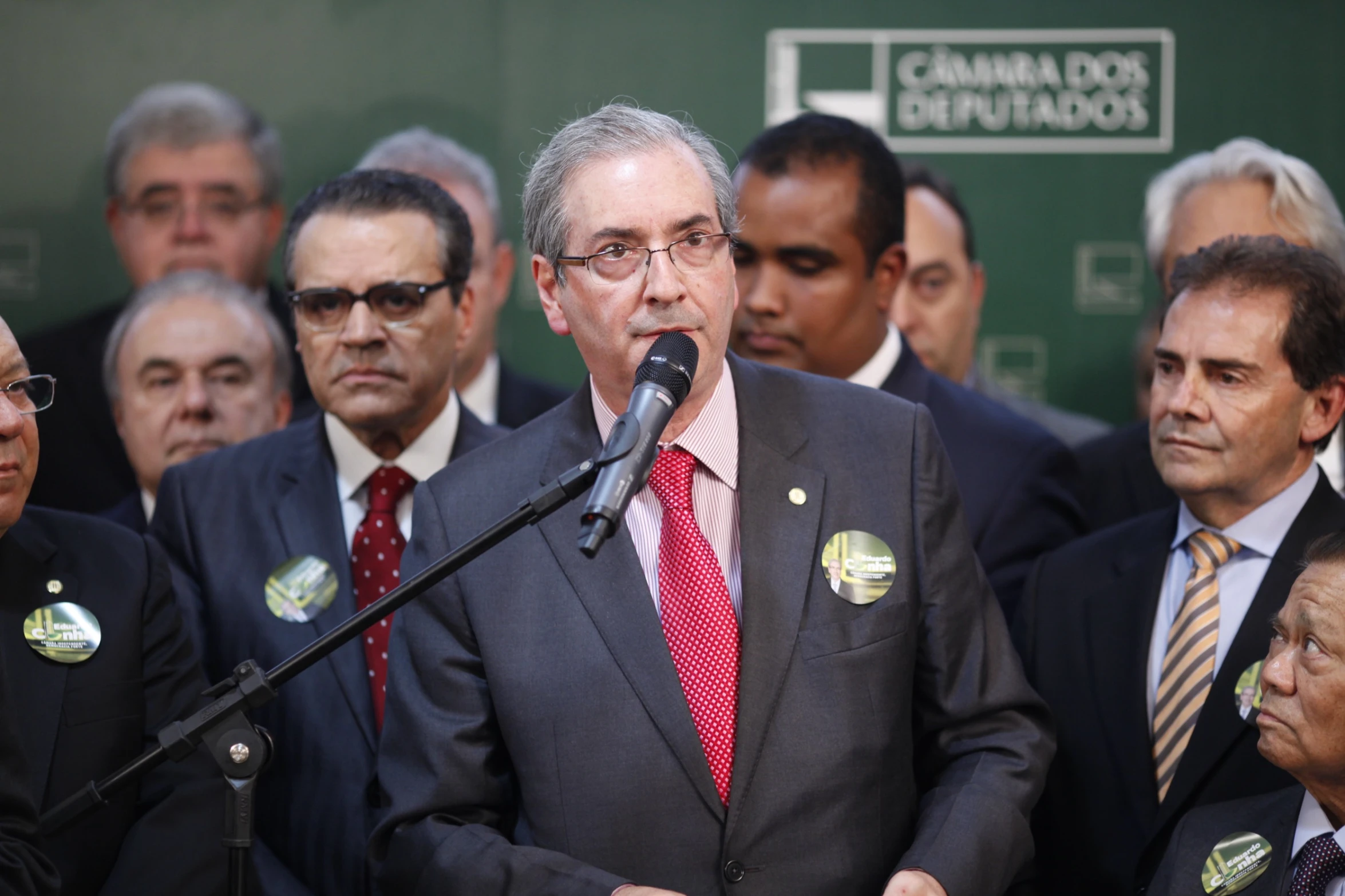 man speaking to a group of people behind a microphone