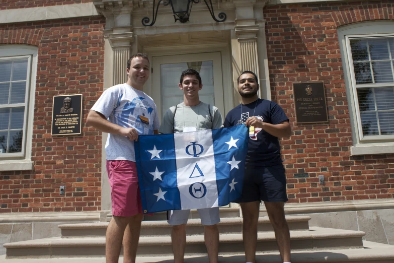 three men are holding a flag in front of a building