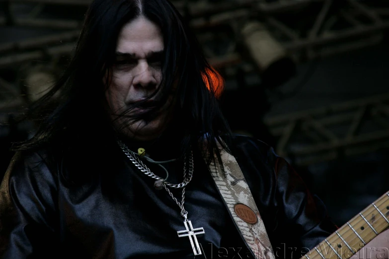 a man with black hair and a cross tattoo is playing guitar