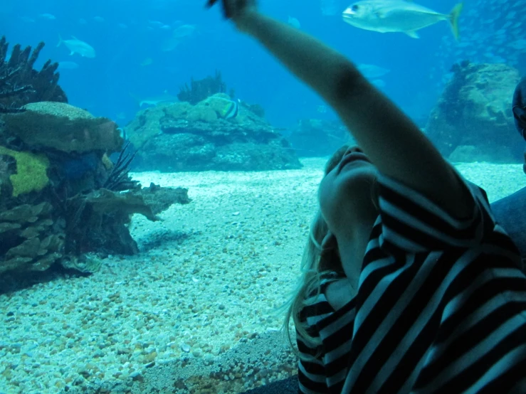 a boy pointing to the ocean in front of a coral reef