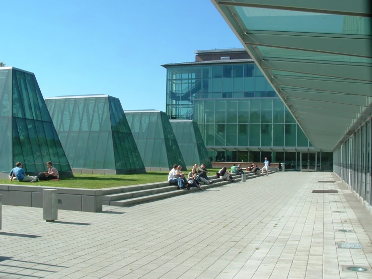 people sit and walk on green brick walkway outside building