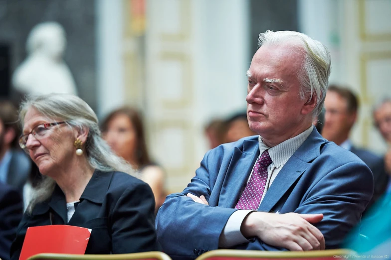 a man in a suit sits next to a woman