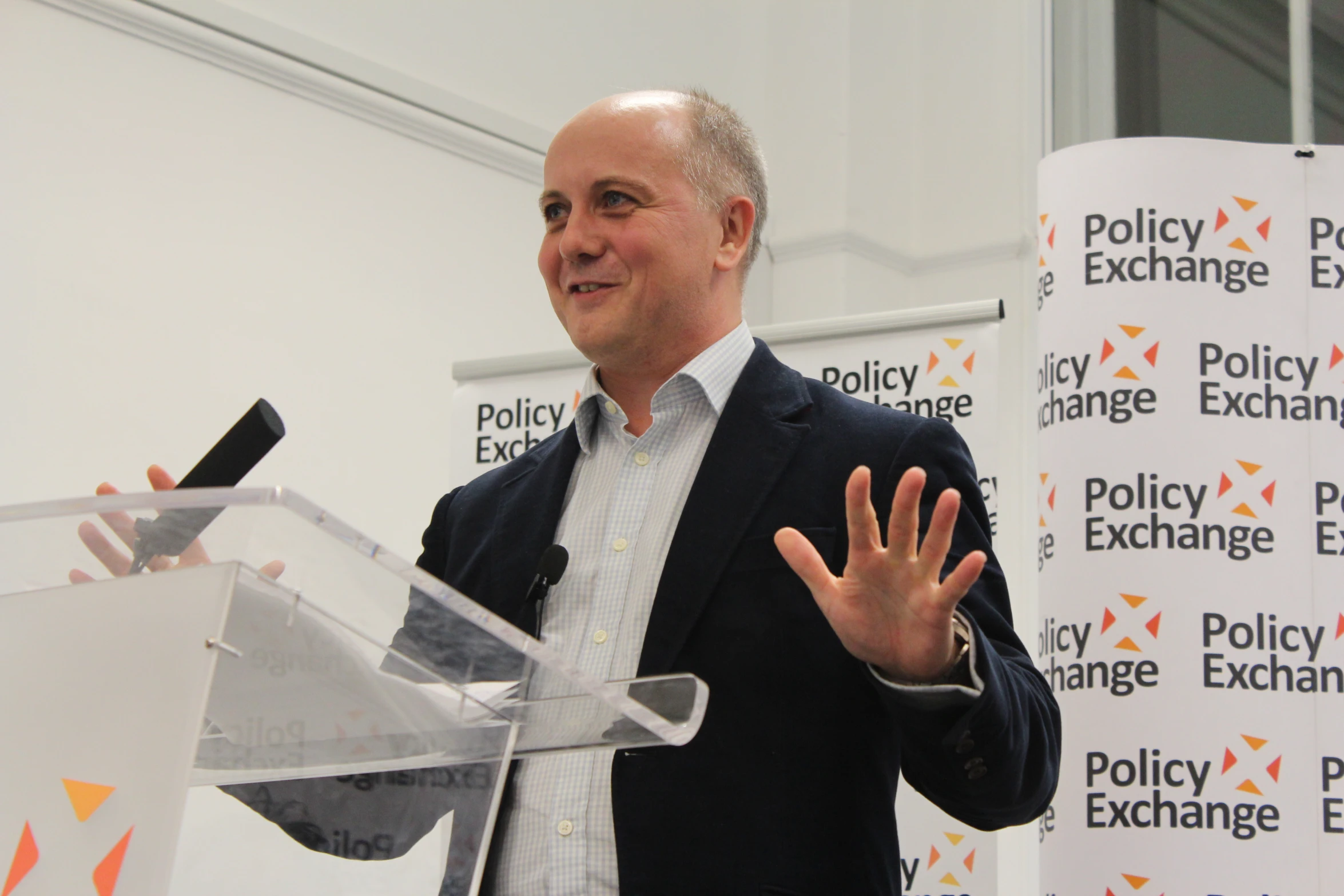 a man in a black suit speaking in front of an audience