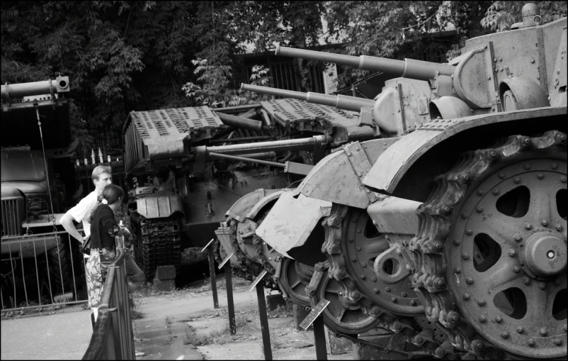 a black and white image of a women in a dress and some very old machinery