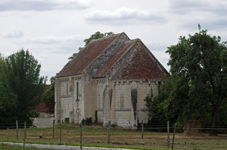 an old church sits behind a barbed wire fence