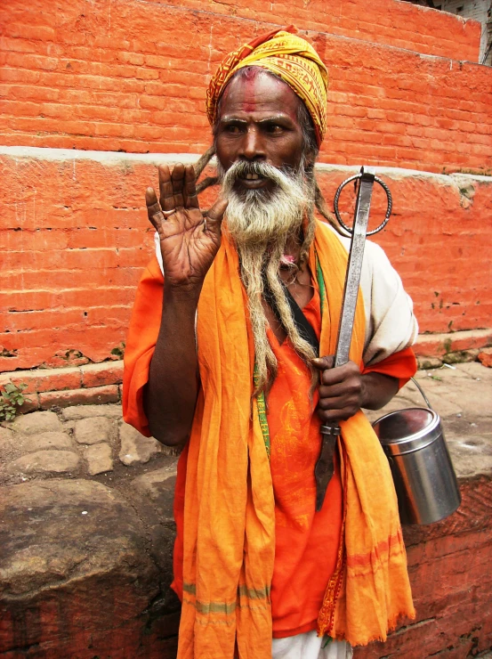 an old man with white beard standing by the brick wall holding a wren