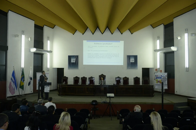 large auditorium with two men at podium giving speech