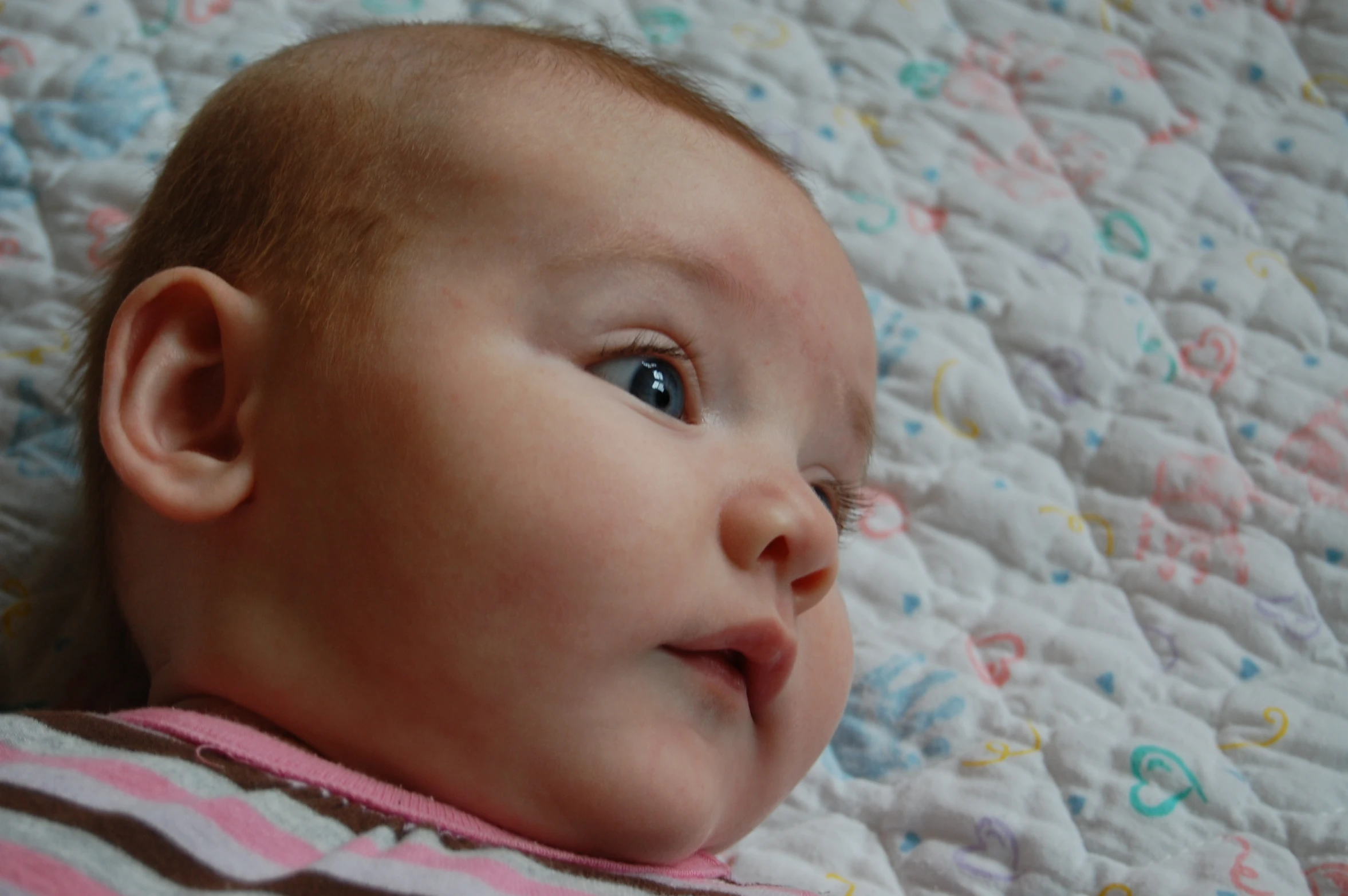 a baby looks at the camera and has his hand on his head