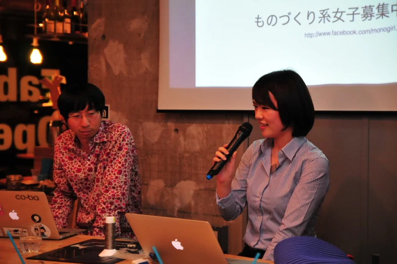 a couple of women sitting next to each other in front of laptops