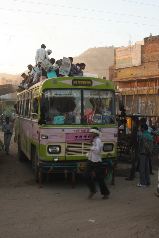 people are waiting to board a passenger bus on a dirt road