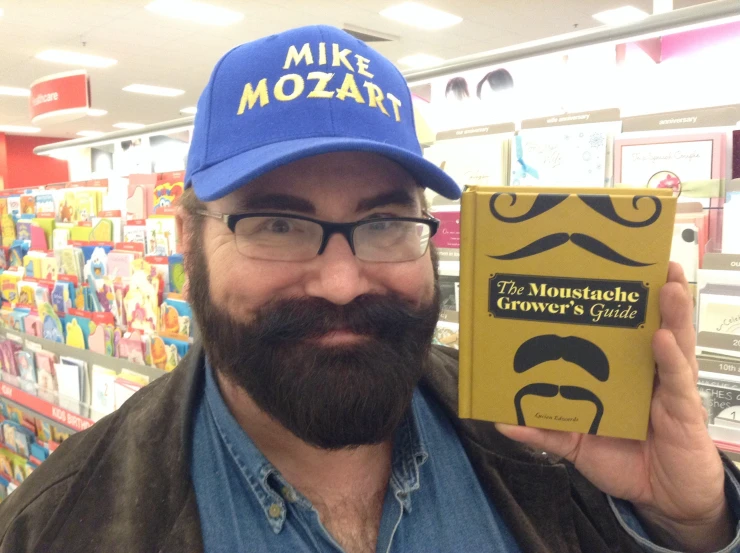 a man wearing glasses and a blue hat holding a book