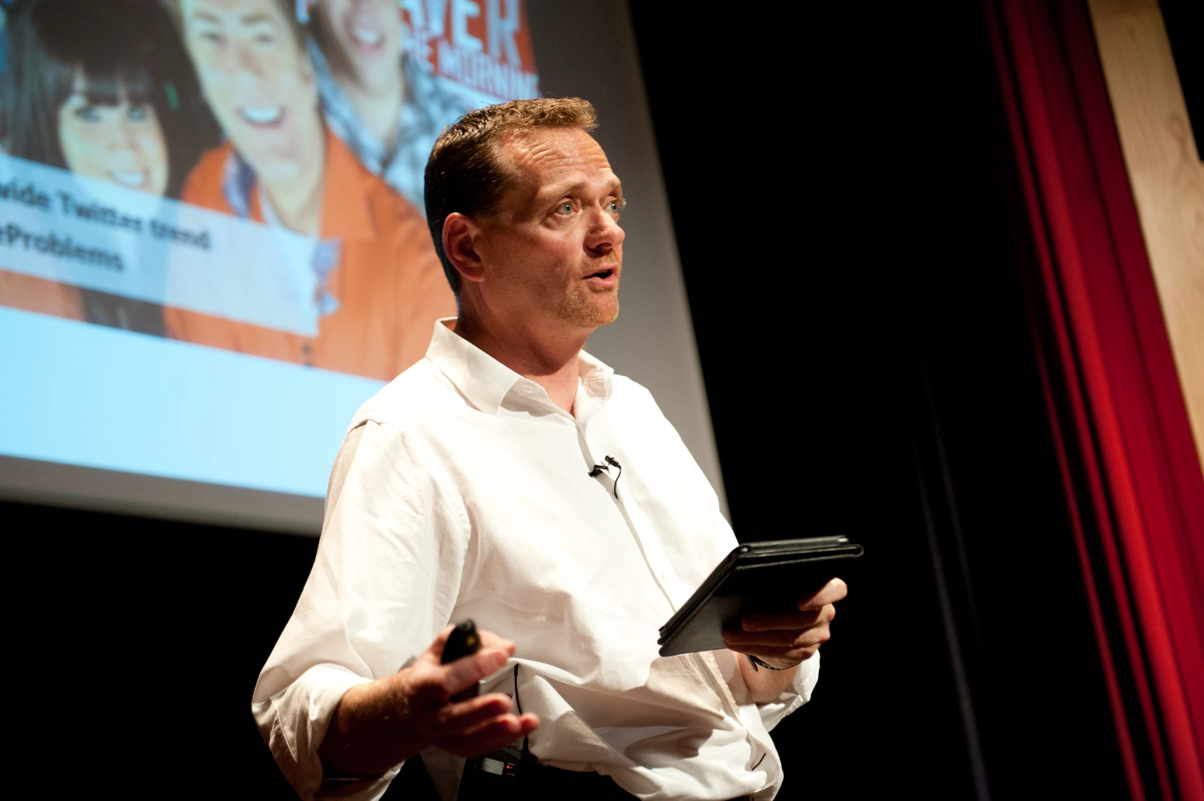 a man stands in front of a presentation and gives a talk