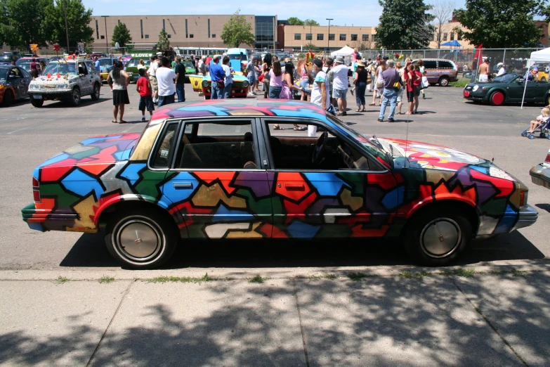 a car painted with colorful designs on it parked in front of other cars