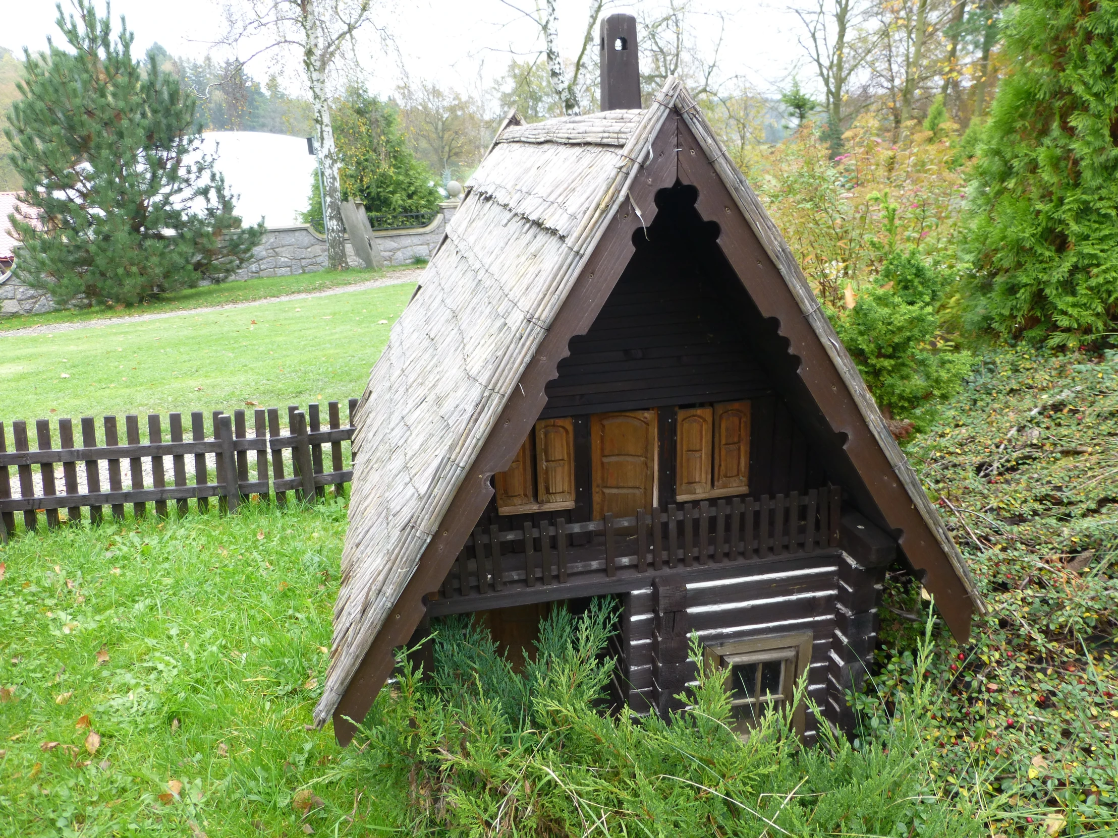 a small, old cabin is in the grass near a fence