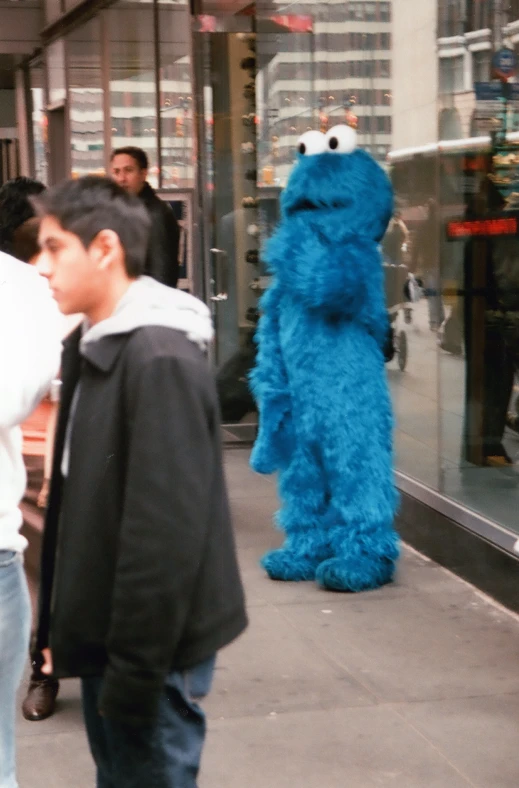 a  walking near an sesame character on a sidewalk