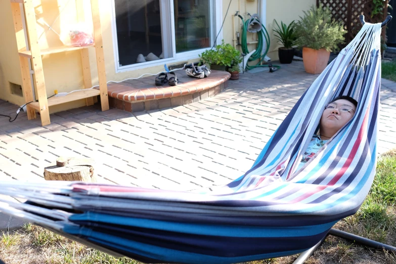 a  is lying in a blue and red hammock