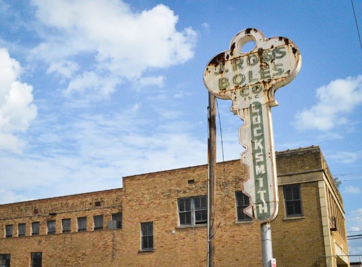 a rusted old sign on a pole near a building