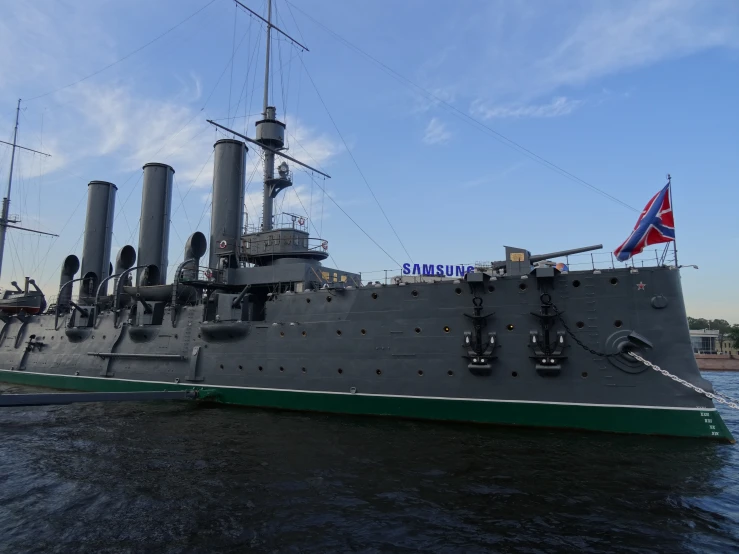 an old grey battleship docked in a body of water