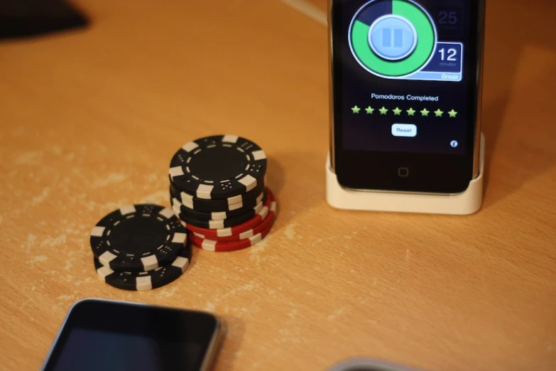 two poker chips sit beside two smart phones