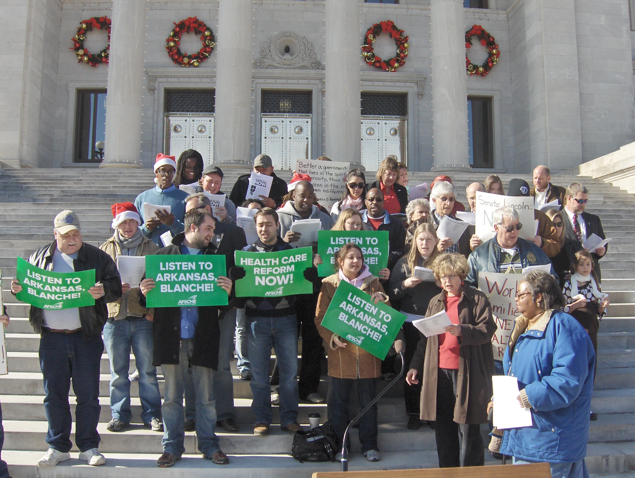 a large group of people holding signs outside of a building