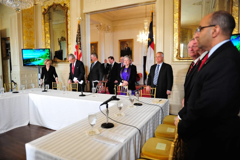 people standing around a white table with water glasses