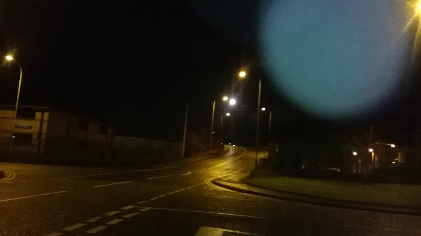 an empty street is lit up by some streetlights