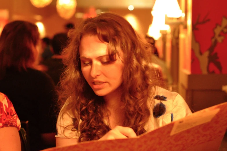 a woman sitting at a table working on a piece of paper