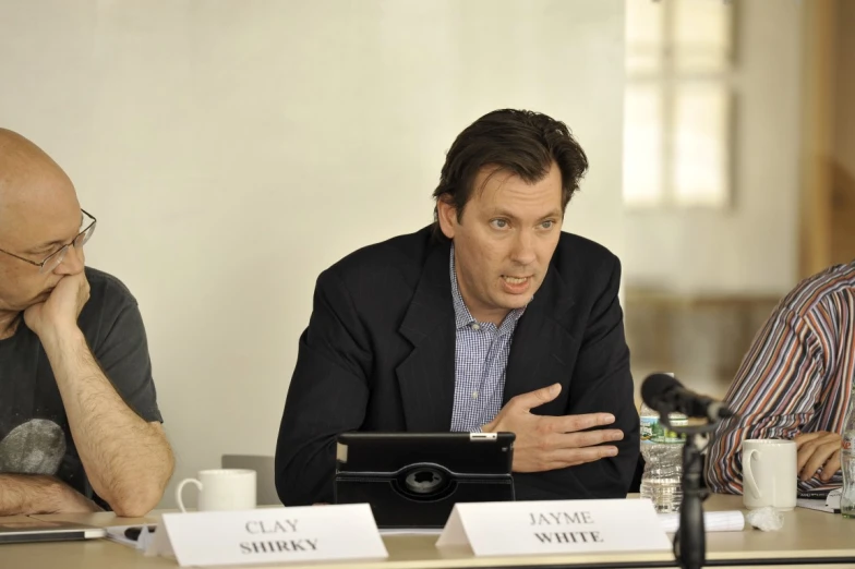 two men are sitting down with a microphone and a tablet