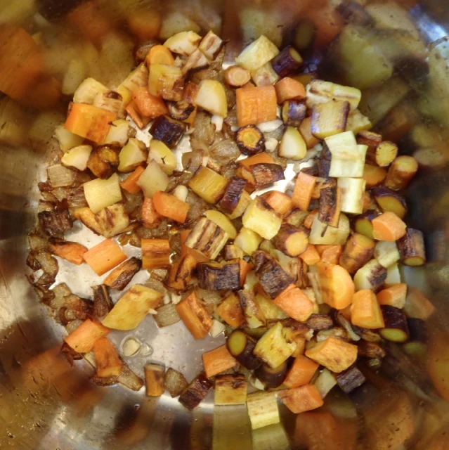 chopped vegetables and meat being mixed together in a pot