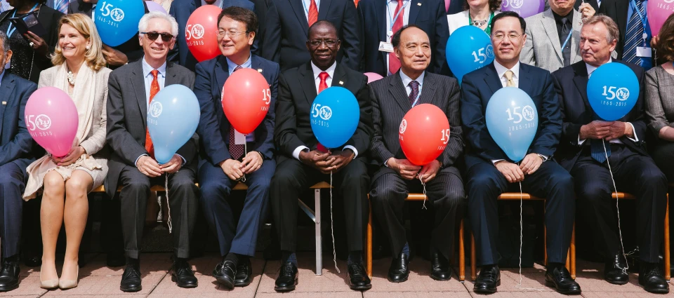 a group of people sit on chairs and hold up balloons