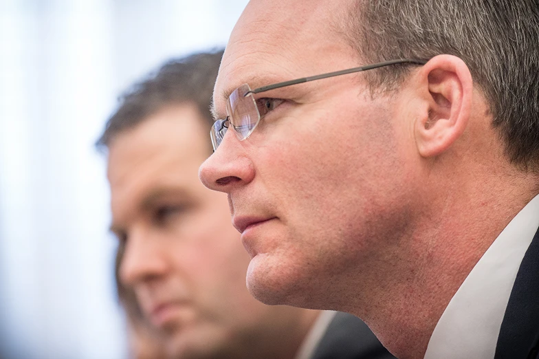 a man in a suit and glasses stands behind other men