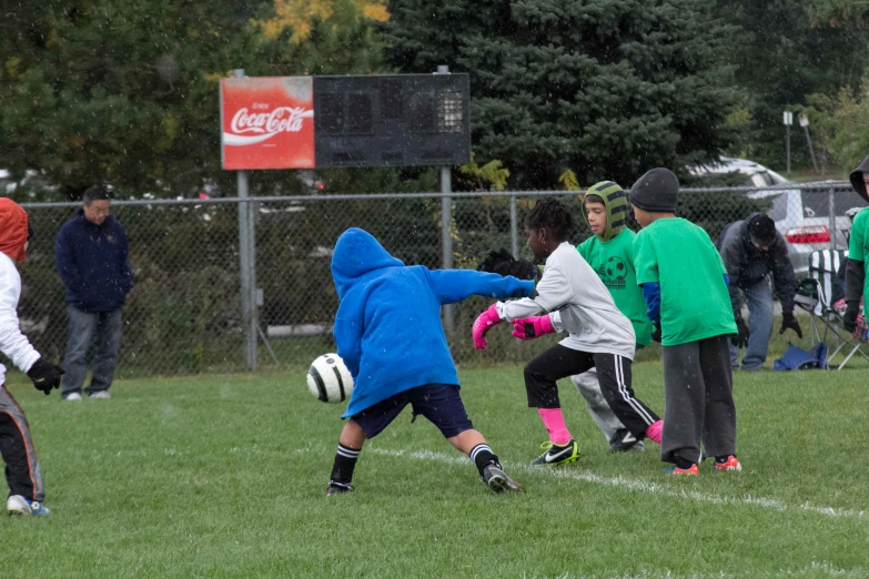 young children on a field playing soccer in the rain