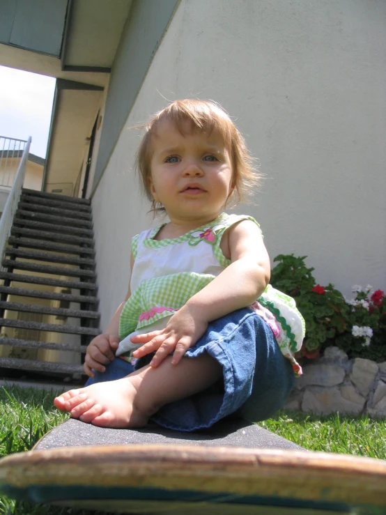 a girl sitting on a ground outside by some stairs