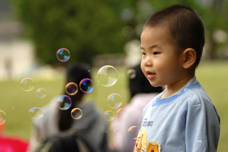 a little boy is looking up at some bubbles