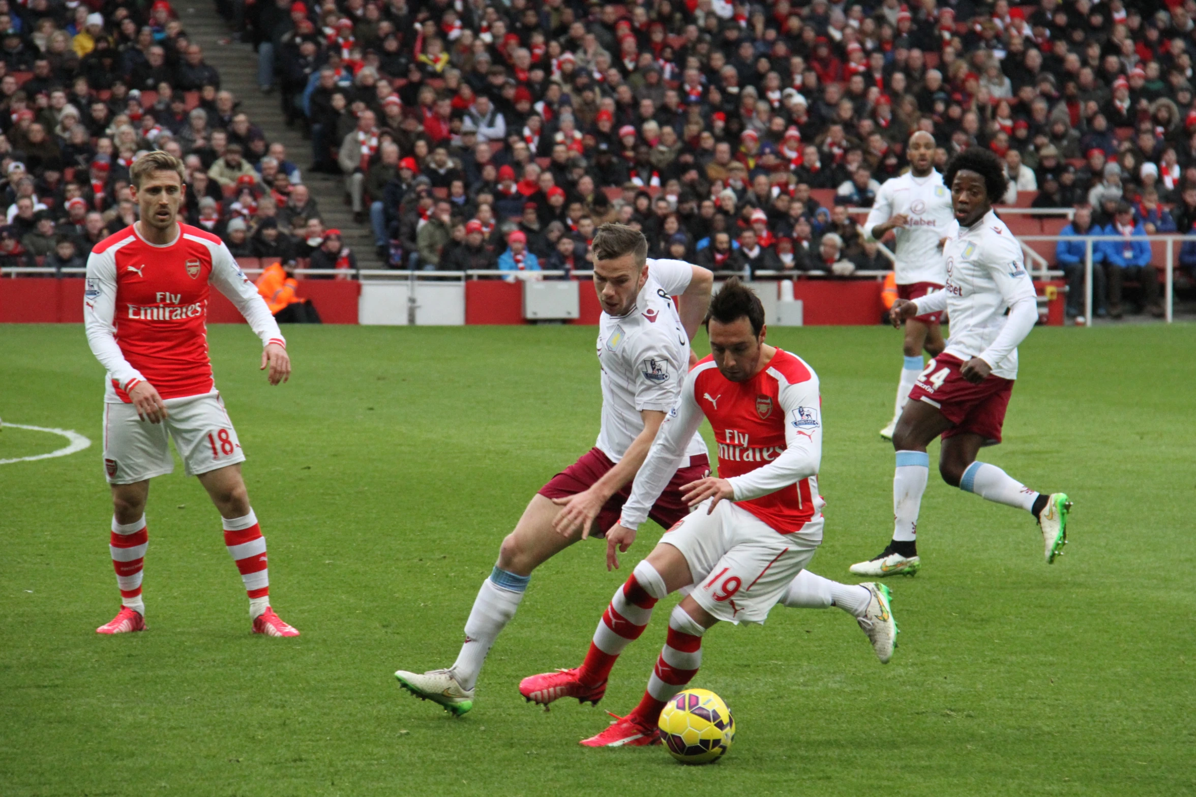 two teams play for the ball while a large crowd watches