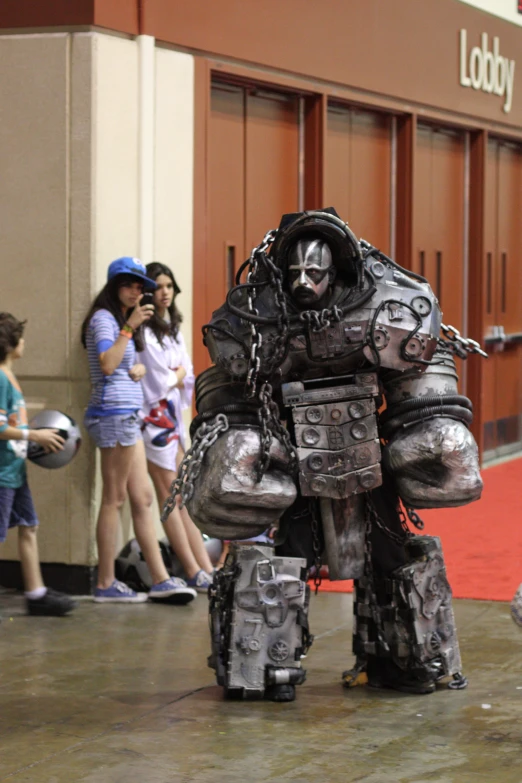 a robot in a silver suit is standing by people