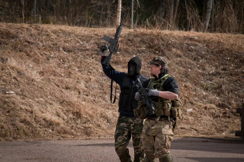 an armed man in camouflage walks with a weapon