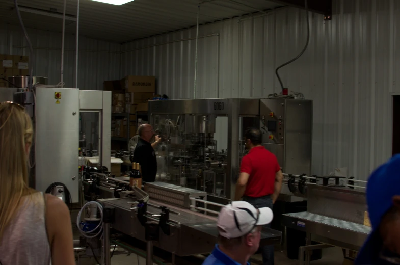 two people standing in front of a factory and two other people looking in the glass doors