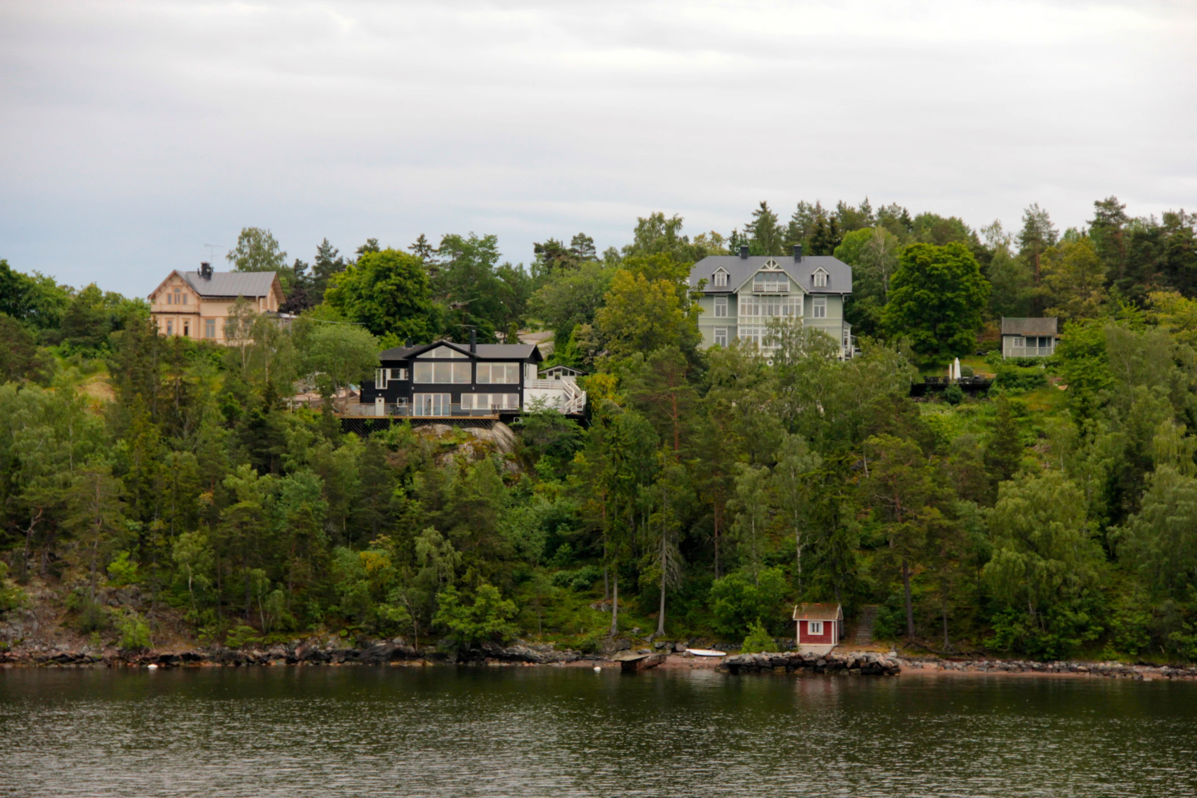 two houses sit on the edge of a wooded hillside