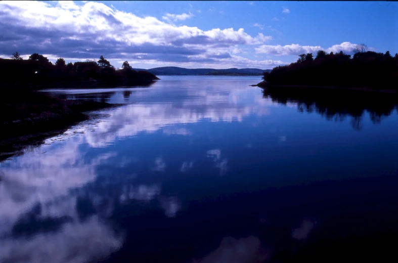 the blue water is reflecting clouds on a cloudy day