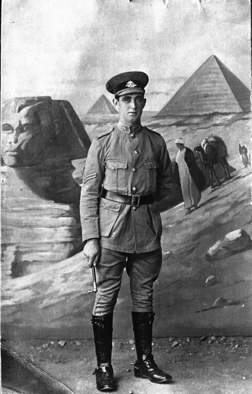 a man in uniform stands with two pyramids and giraffes behind him